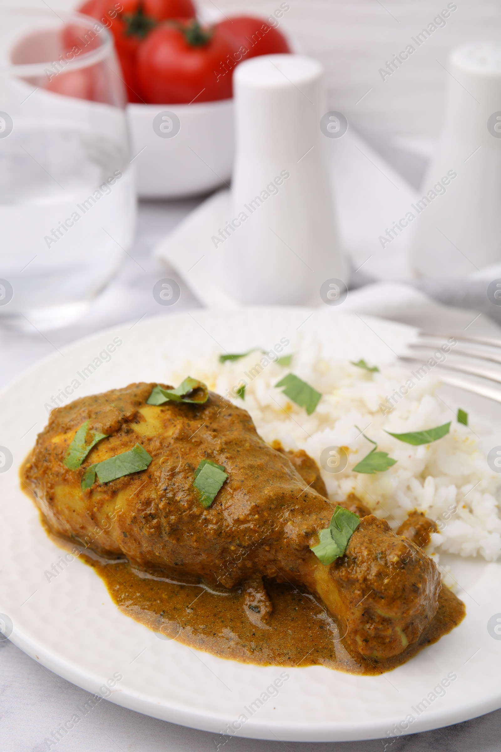 Photo of Delicious rice and chicken with curry sauce served on white table, closeup