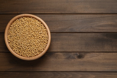 Photo of Soy in bowl on wooden table, top view. Space for text