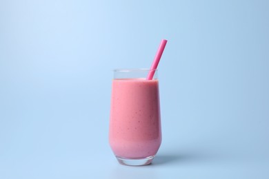 Photo of Glass with delicious fresh berry smoothie on light blue background