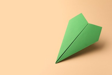 Photo of Handmade green paper plane on beige background, space for text