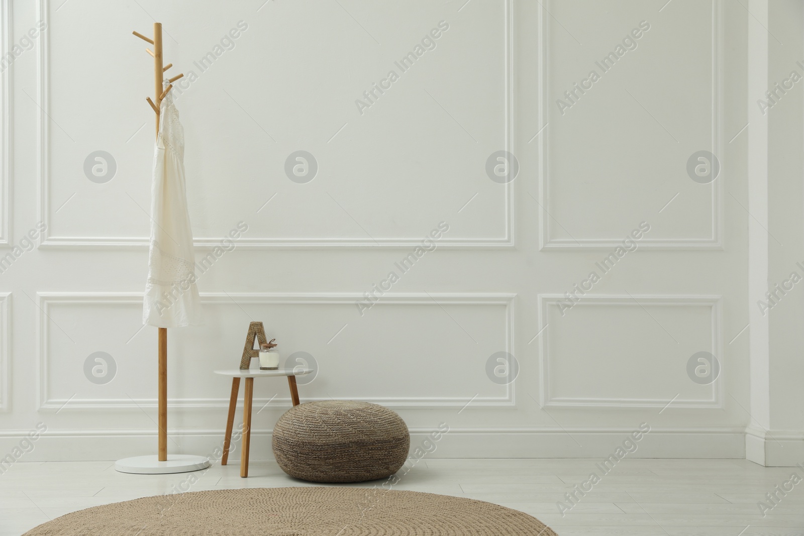 Photo of Simple hall interior with pouf, clothes rack and decor elements. Space for text