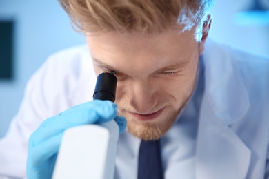 Male scientist using modern microscope in chemistry laboratory