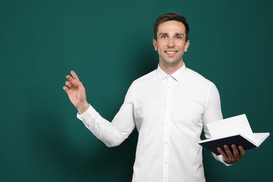 Photo of Portrait of male teacher with book on color background