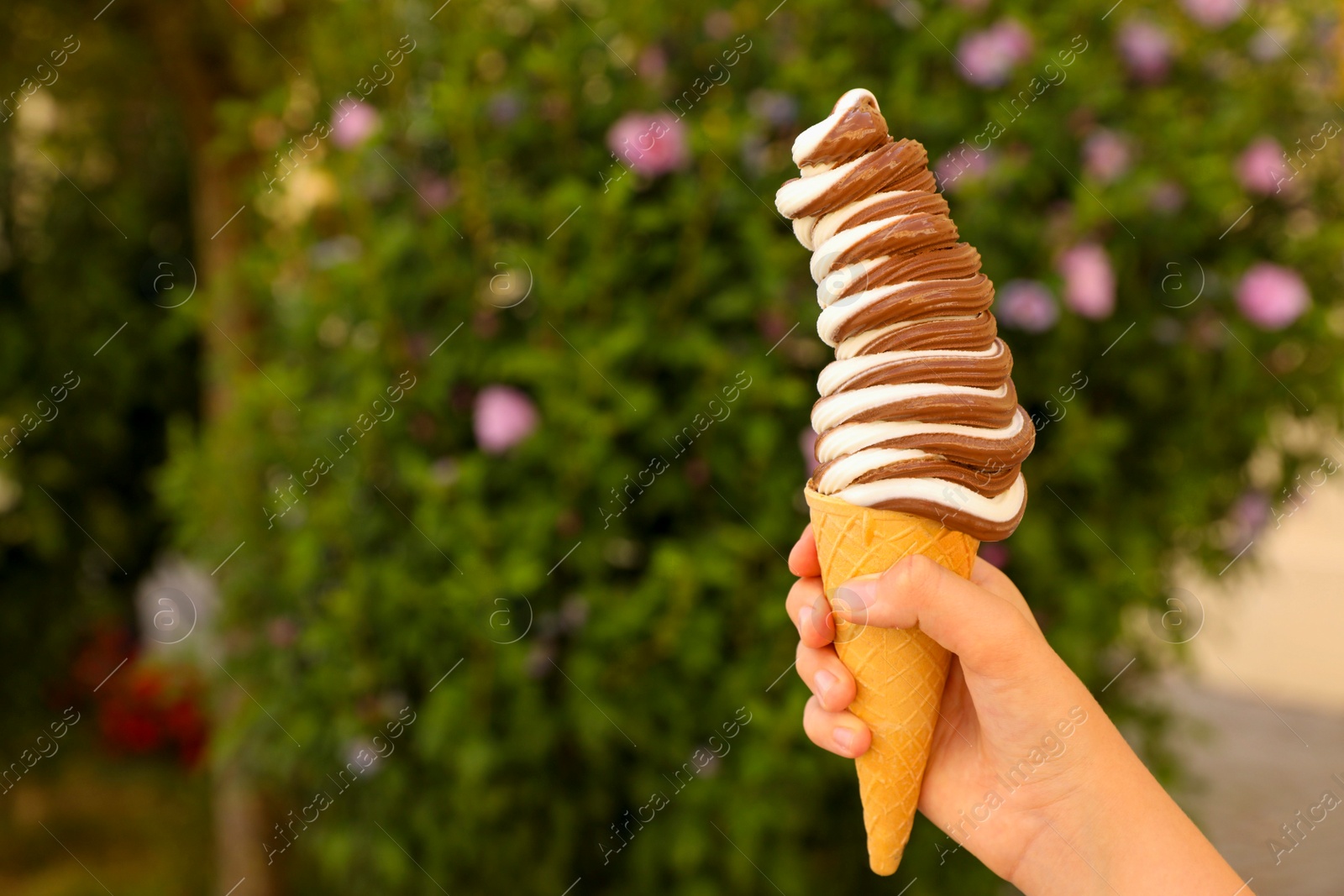 Photo of Woman holding delicious ice cream outdoors, closeup. Space for text