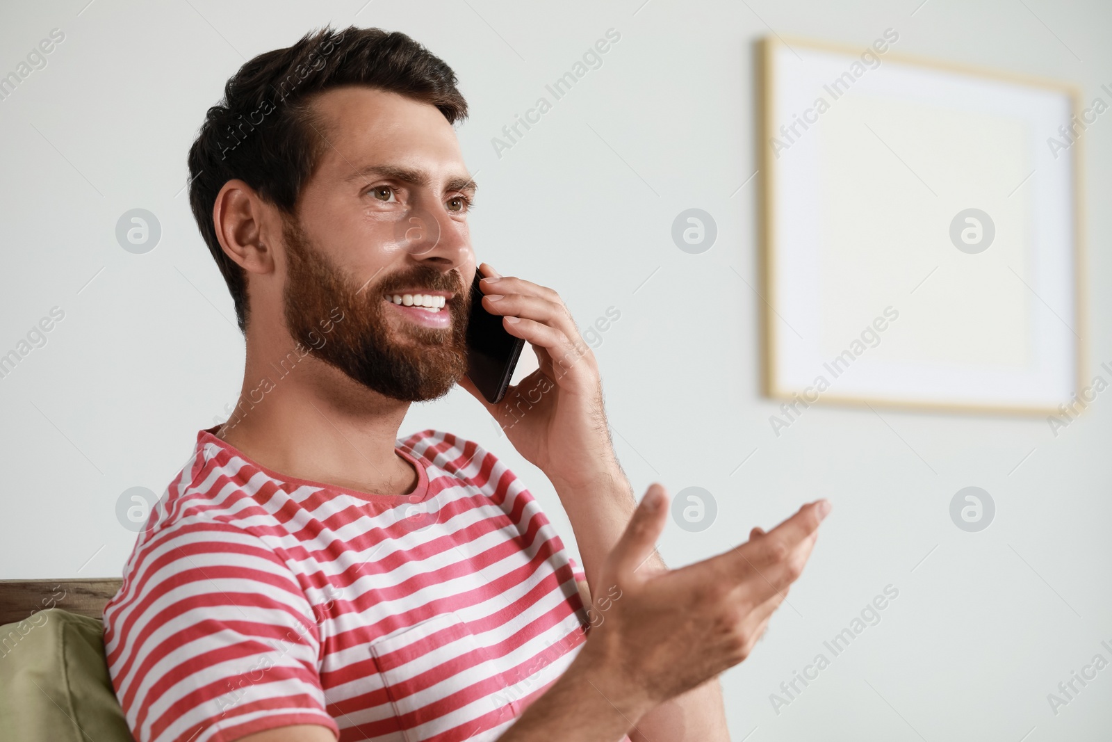 Photo of Handsome man talking on phone at home, space for text