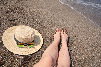 Photo of Woman with straw hat and heart shaped sunglasses on sea beach, closeup