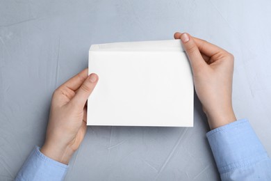 Photo of Woman with envelope at grey table, top view