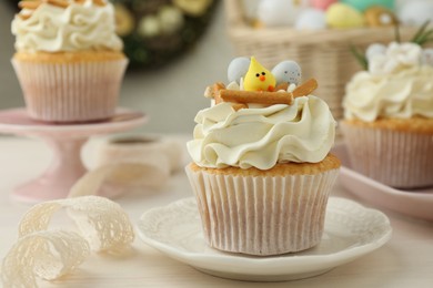 Photo of Tasty Easter cupcakes with vanilla cream on light wooden table