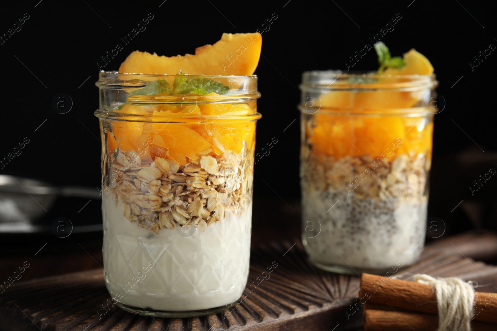 Photo of Tasty peach dessert with yogurt, chia seeds and granola on black background