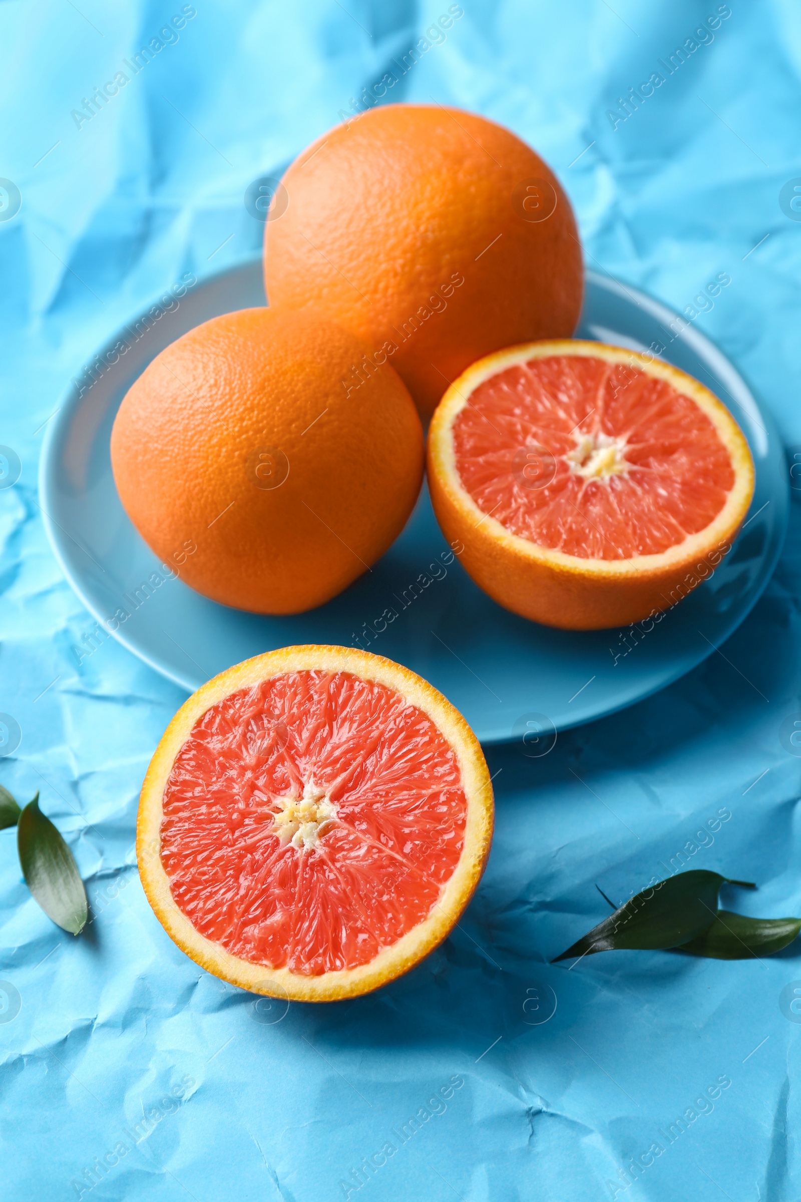 Photo of Plate with fresh yummy oranges on color paper  background