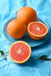 Plate with fresh yummy oranges on color paper  background