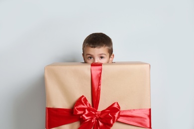 Image of Cute little boy dressed as gift box near white wall. Christmas suit