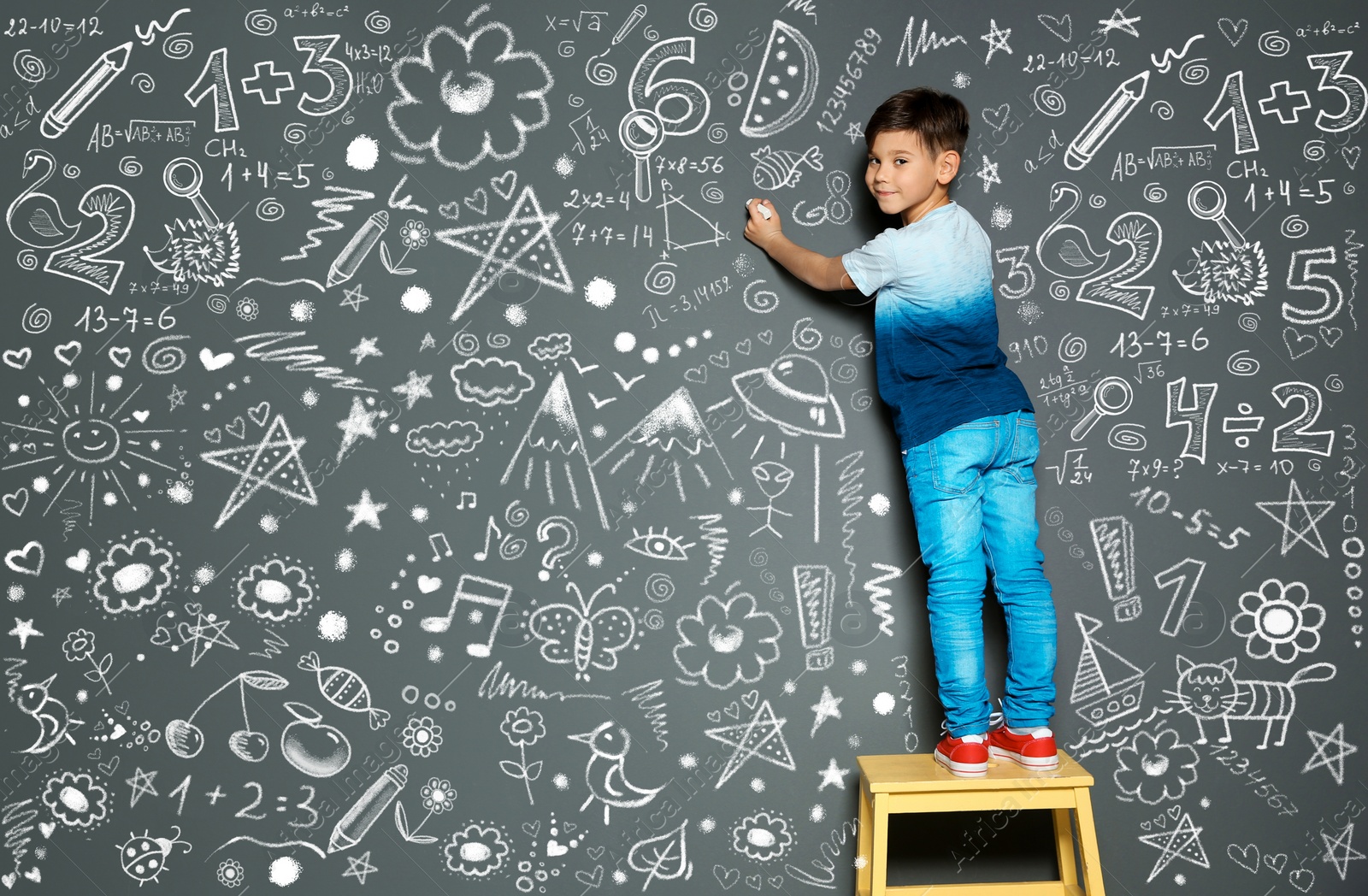 Image of Little child drawing with chalk on gray wall