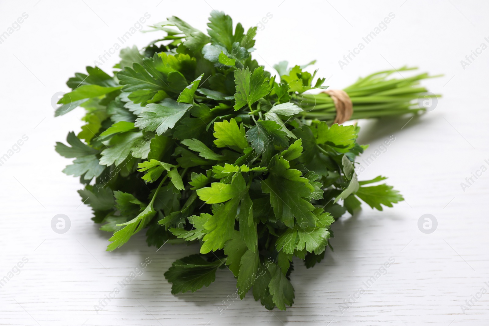 Photo of Bunch of fresh green parsley on white wooden table, closeup