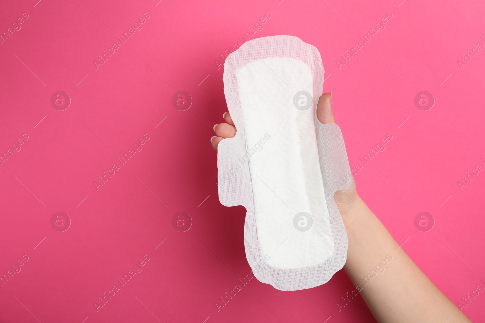 Photo of Woman holding sanitary napkin on pink background, closeup. Space for text