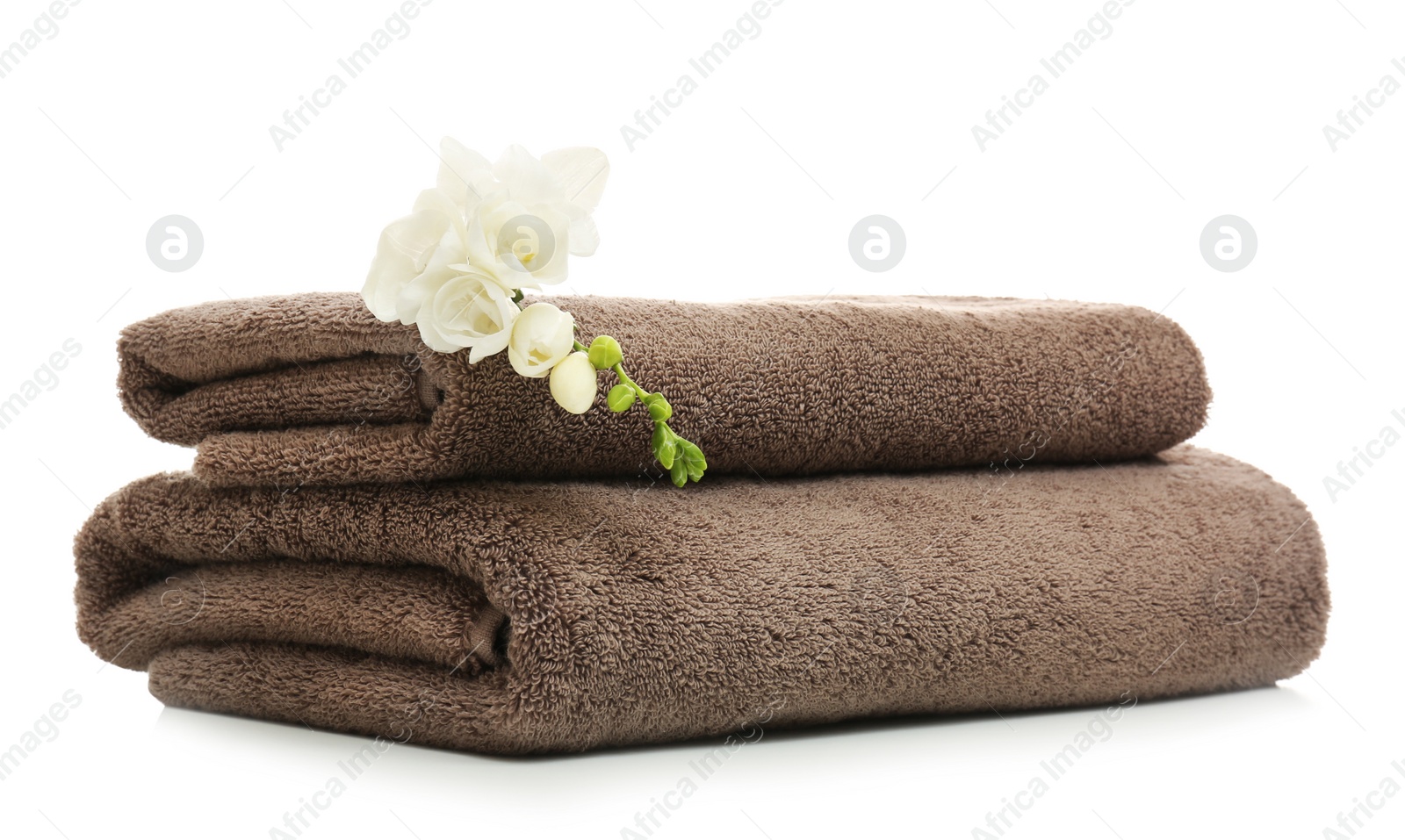 Photo of Clean folded towels with flowers on white background