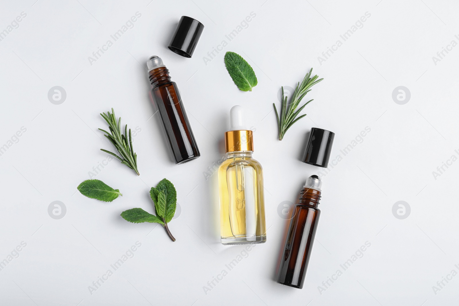Photo of Little bottles of essential oils with different herbs on white background, top view