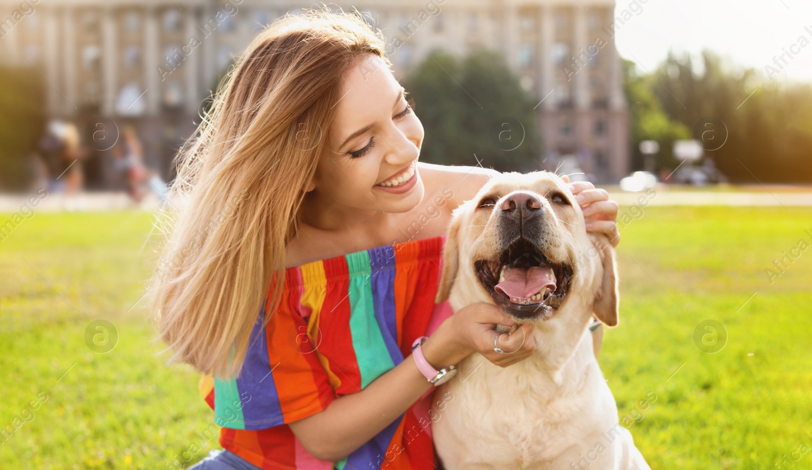 Image of Young woman with her cute yellow labrador outdoors. Lovely pet