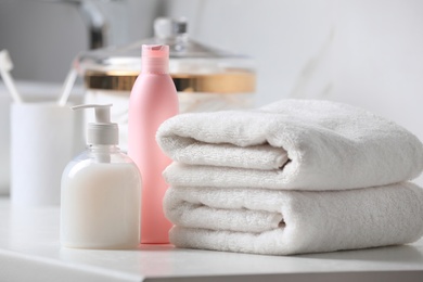 Photo of Folded towels and toiletries on white table in bathroom