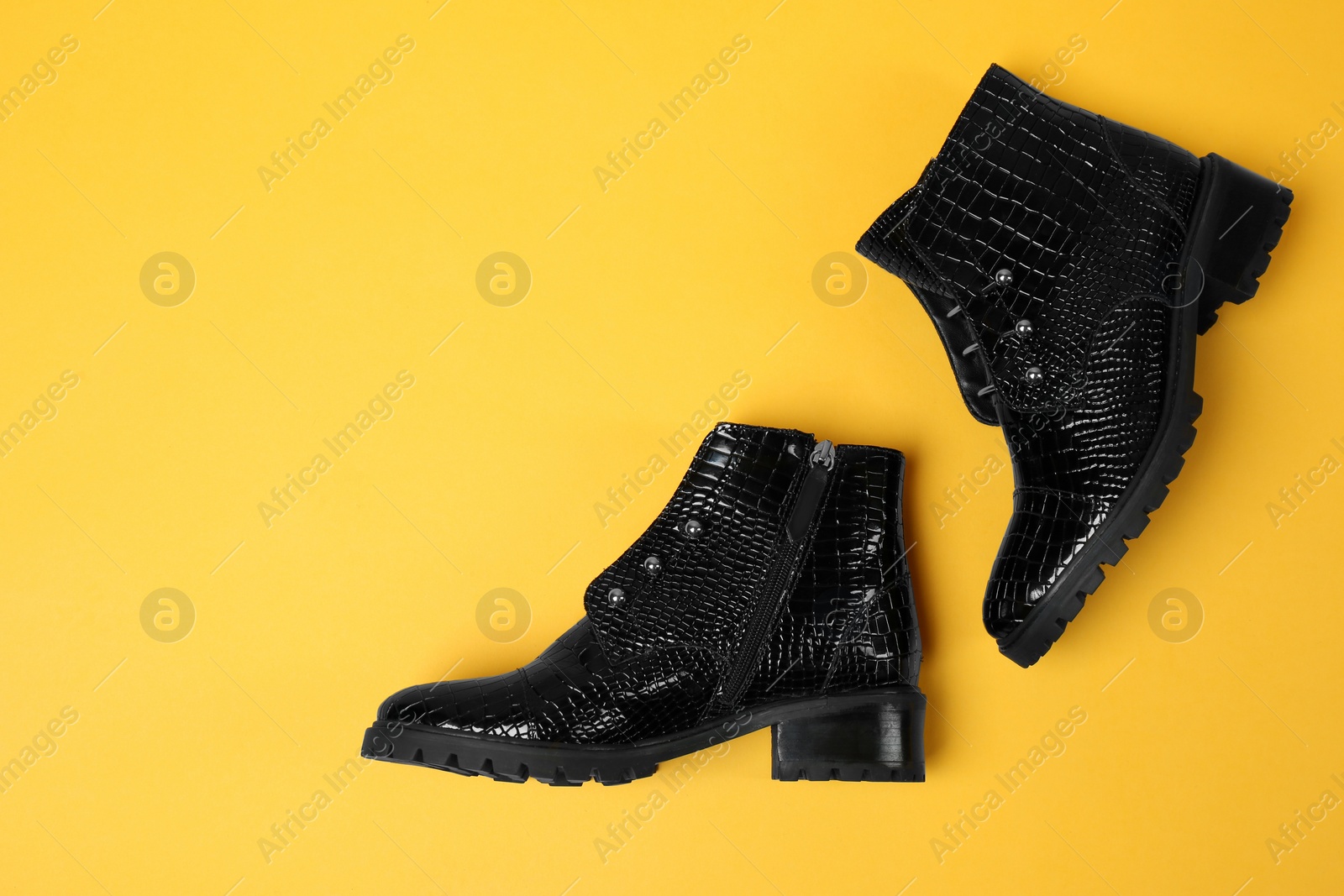 Photo of Pair of stylish ankle boots on yellow background, top view. Space for text