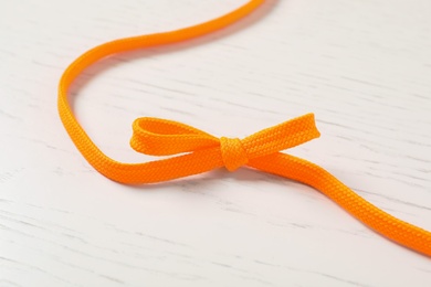 Photo of Orange shoelace on white wooden background. Stylish accessory