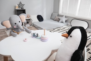 Photo of Cute toys at white table in Montessori bedroom. Interior design