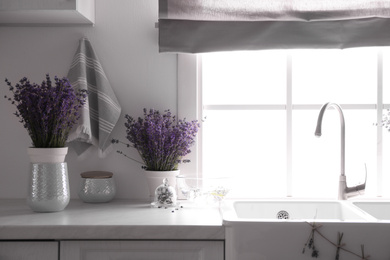 Beautiful lavender flowers on countertop near sink in kitchen