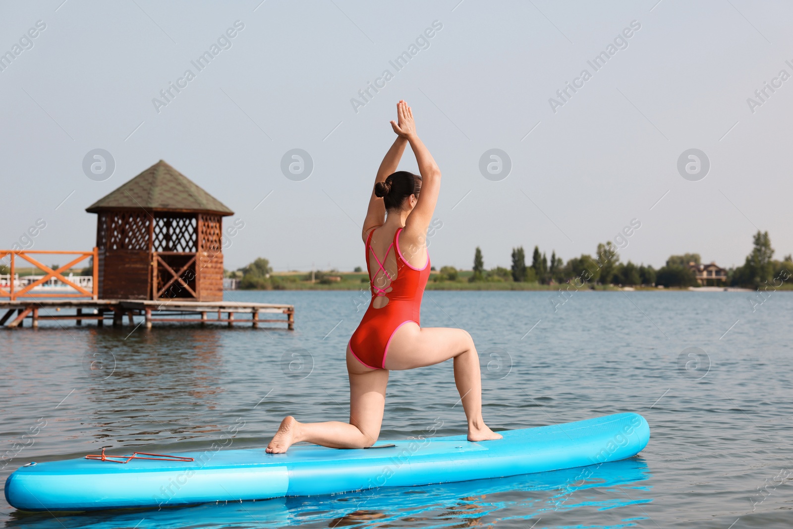 Photo of Woman practicing yoga on light blue SUP board on river