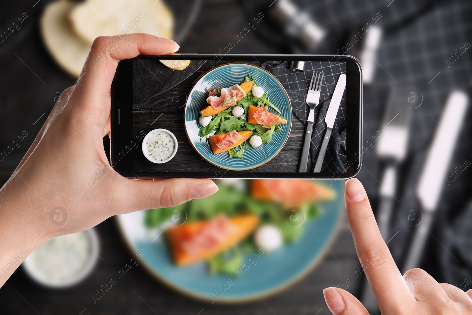 Image of Blogger taking picture of fresh melon with prosciutto at table, closeup. Food photography