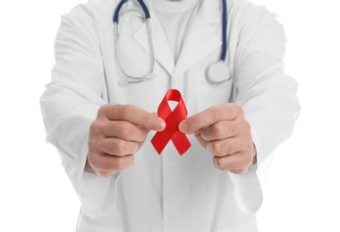 Doctor holding red awareness ribbon on white background, closeup. World AIDS disease day