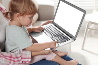 Photo of Mother and daughter with laptop on sofa at home. Pediatrician online consultation