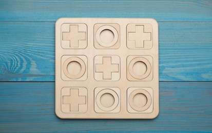 Tic tac toe set on light blue wooden table, top view