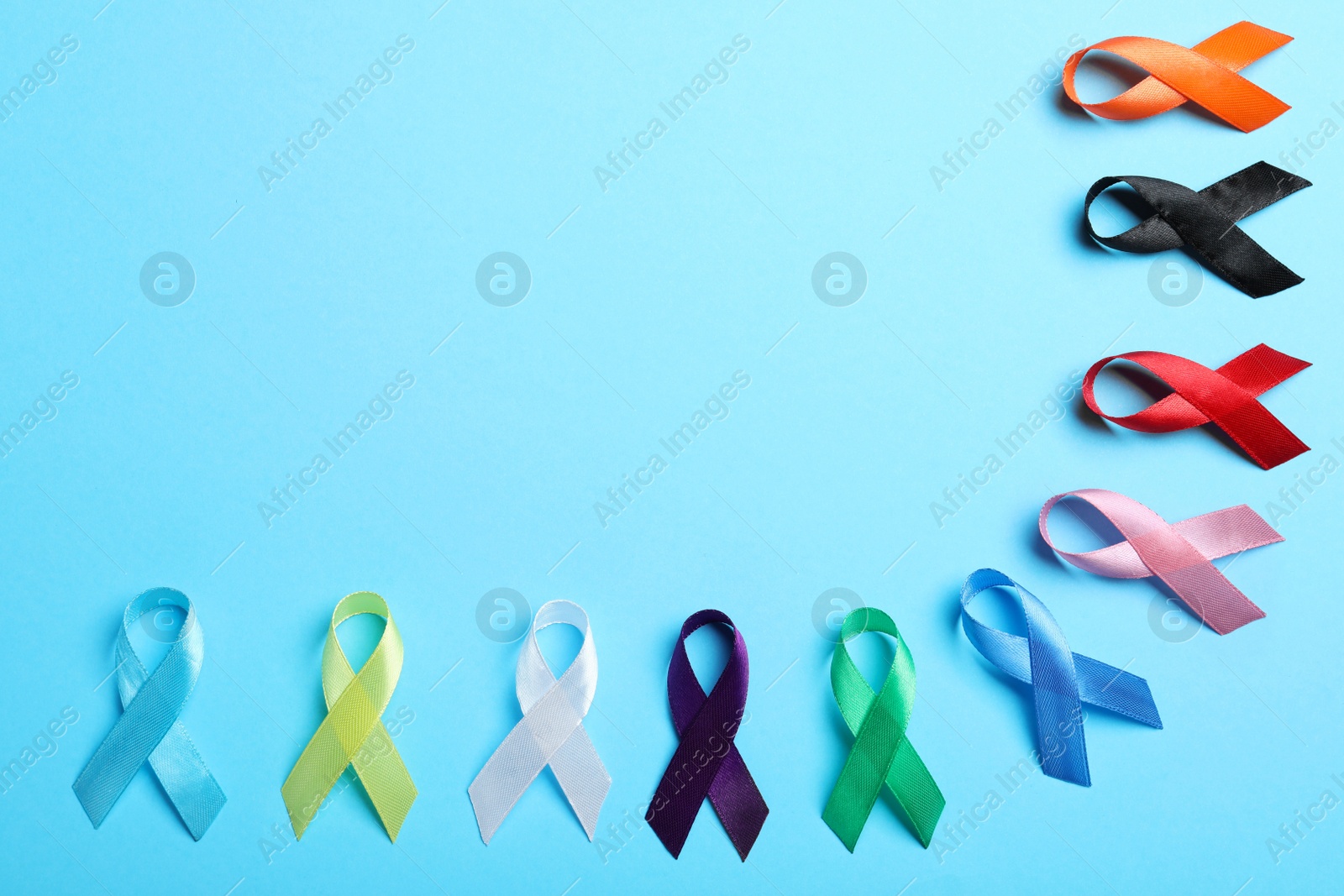 Photo of Colorful ribbons on light blue background, flat lay with space for text. World Cancer Day