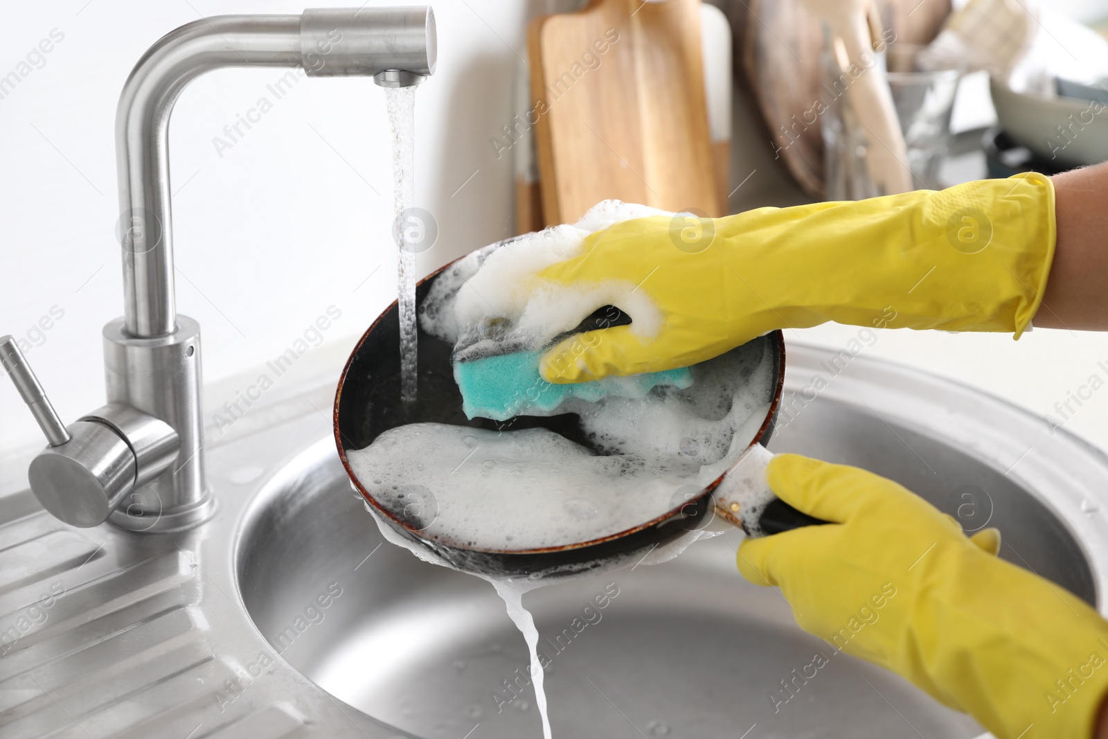 Photo of Woman washing dirty frying pan in sink indoors, closeup