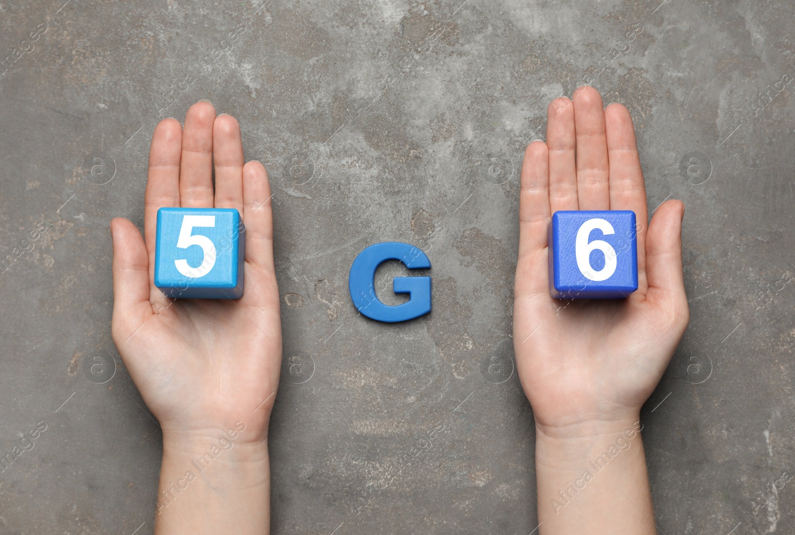 Photo of Internet concept. Woman holding blue wooden cubes and letter on grey table, top view