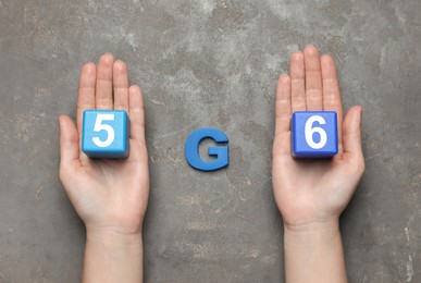Photo of Internet concept. Woman holding blue wooden cubes and letter on grey table, top view
