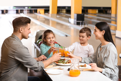 Photo of Happy family with pizza and drinks in bowling club