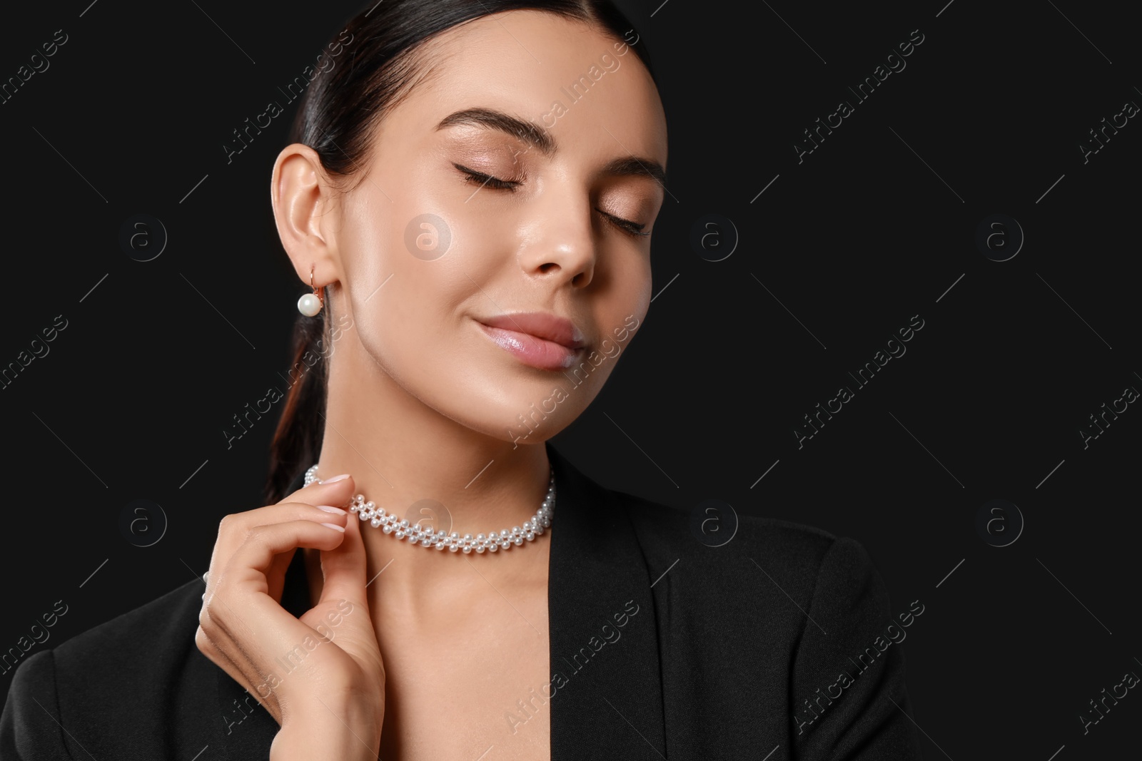 Photo of Young woman with elegant pearl jewelry on black background, space for text