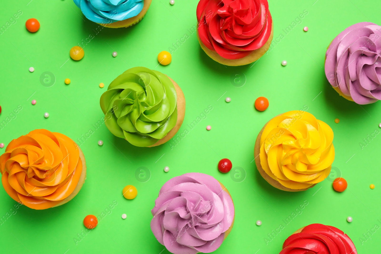 Photo of Colorful birthday cupcakes on green background, flat lay