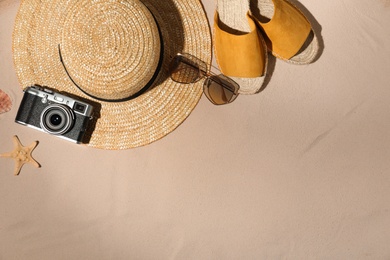 Flat lay composition with vintage camera and beach objects on sand. Space for text