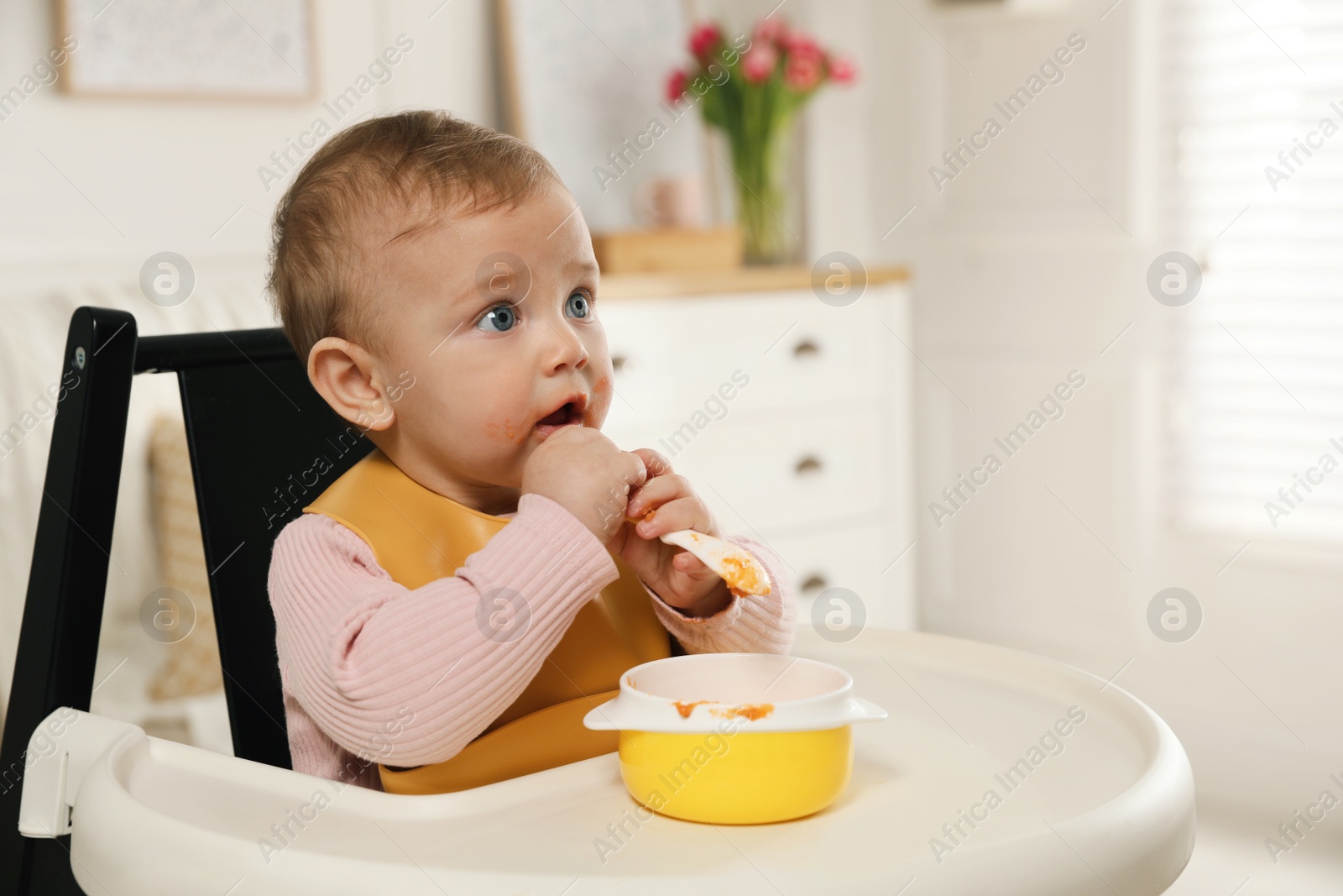 Photo of Cute little baby wearing bib while eating at home