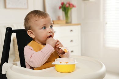 Photo of Cute little baby wearing bib while eating at home