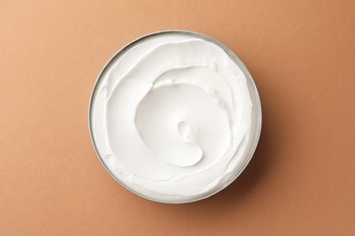 Jar of face cream on beige background, top view