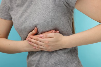 Photo of Woman having heart attack on light blue background, closeup