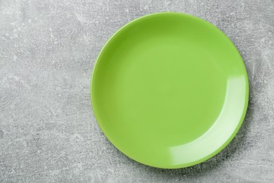 Photo of Empty green ceramic plate on light grey table, top view. Space for text
