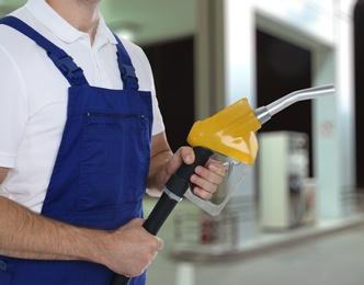 Image of Worker holding fuel nozzle near gas station, closeup