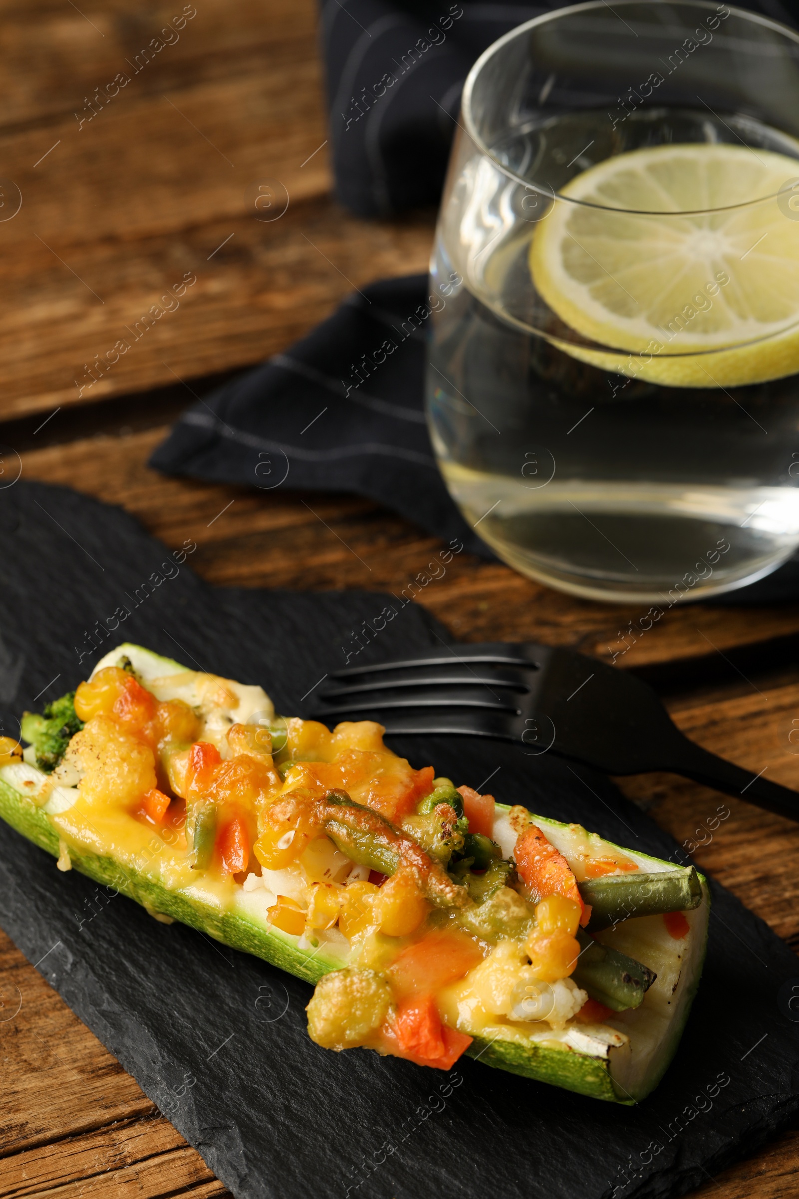 Photo of Baked stuffed zucchini served on wooden table, closeup