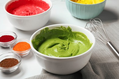 Photo of Bowls of different cream with food coloring on white marble table