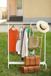 Photo of Clothing rack with different garments in yard. Garage sale