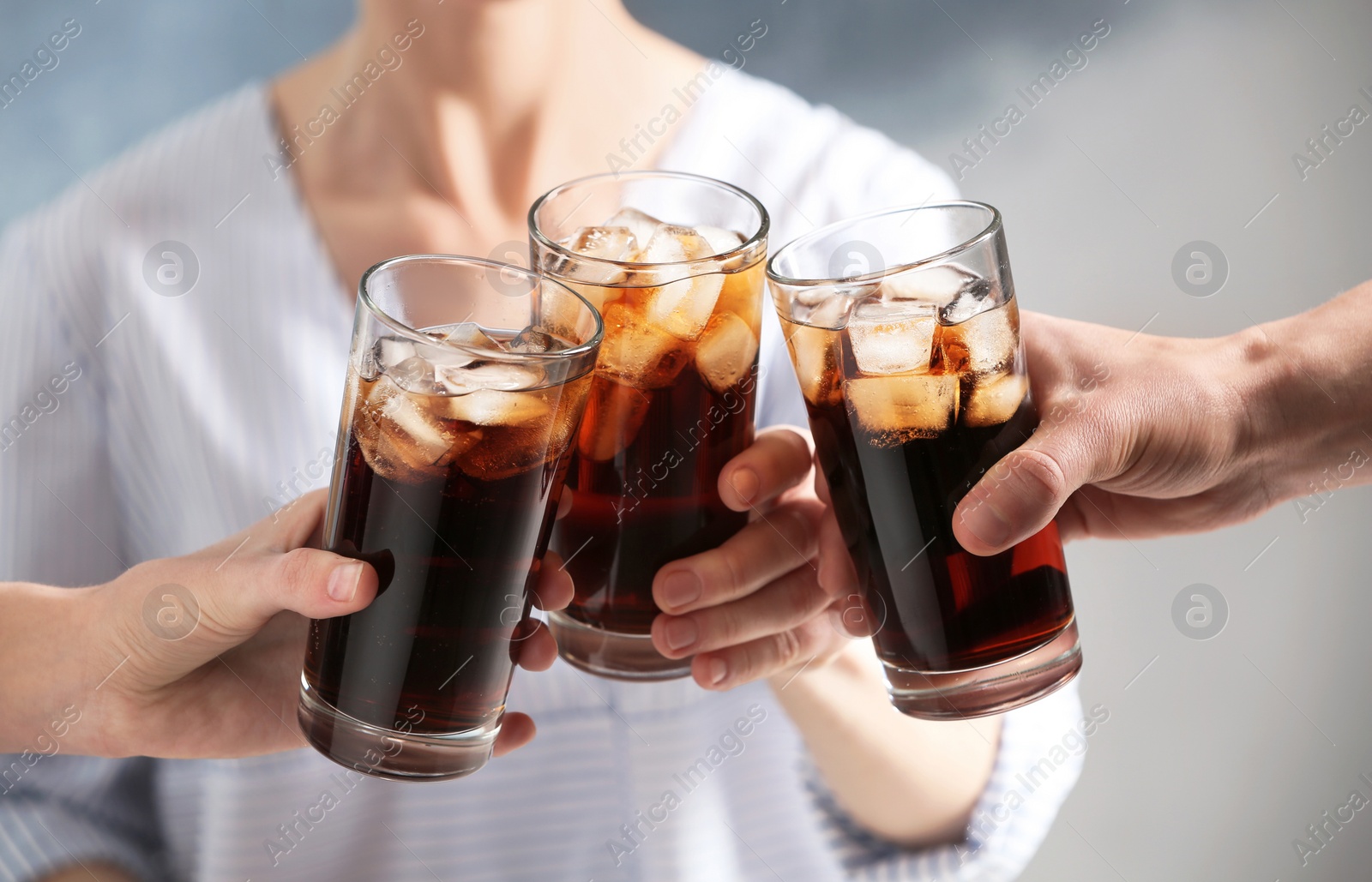 Photo of Friends with glasses of cold cola on color background, closeup